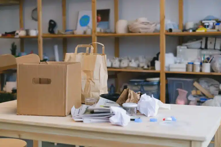 Volle afvalbakken met kartonnen dozen en verpakkingsmaterialen bij een gemeentelijk inzamelpunt