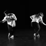 Twee dansers voeren een hedendaagse duet uit in een dansatelier