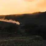 Silhouet van gefossiliseerde haaientanden en tenten bij woestijnduinen in de schemering