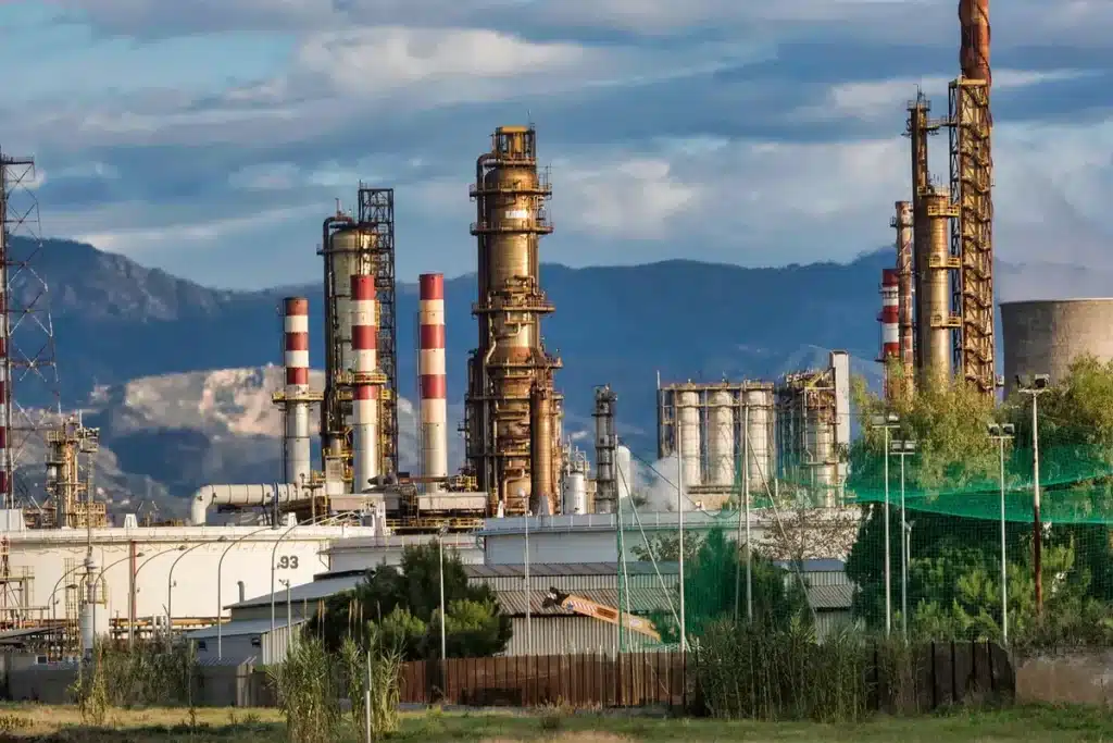 Grote industriële raffinaderij met koeltorens tegen een grijze hemel, symboliserend de energietransitie