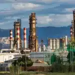Grote industriële raffinaderij met koeltorens tegen een grijze hemel, symboliserend de energietransitie
