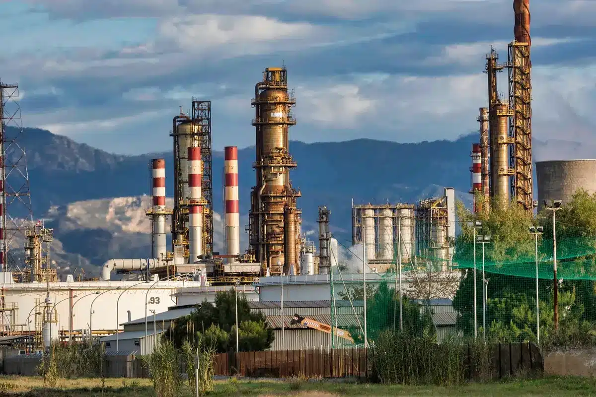 Grote industriële raffinaderij met koeltorens tegen een grijze hemel, symboliserend de energietransitie