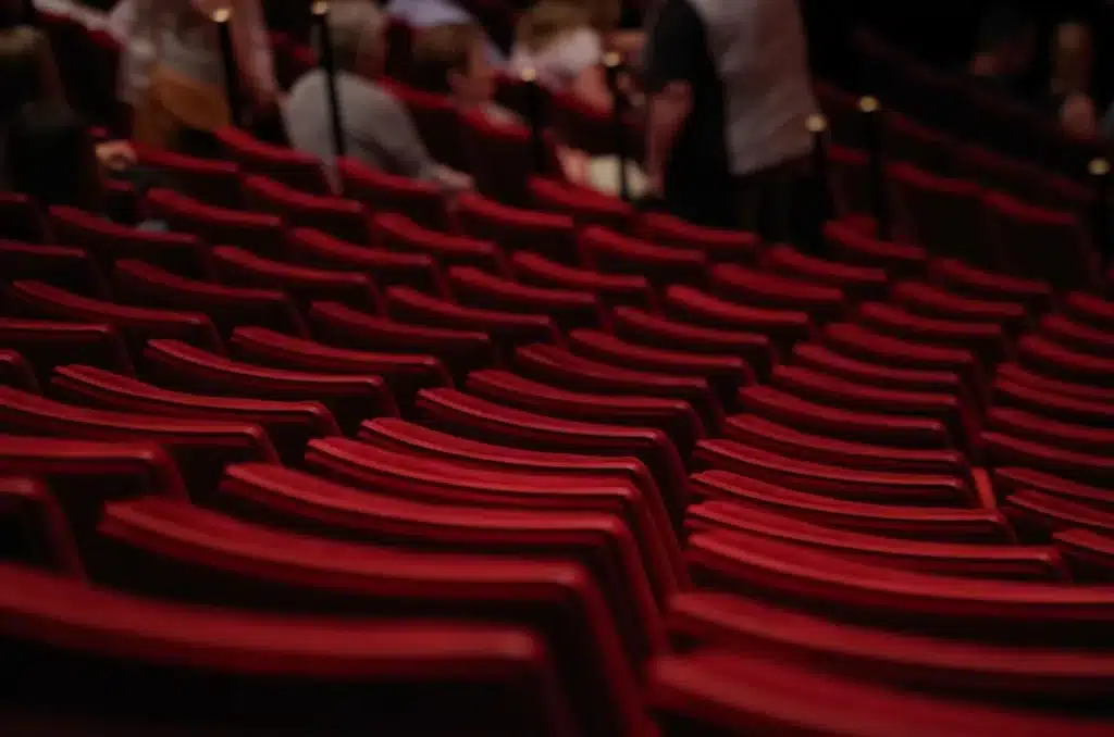 Leeg toneel met microfoon en silhouetten van publiek in een klein theater