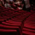 Leeg toneel met microfoon en silhouetten van publiek in een klein theater