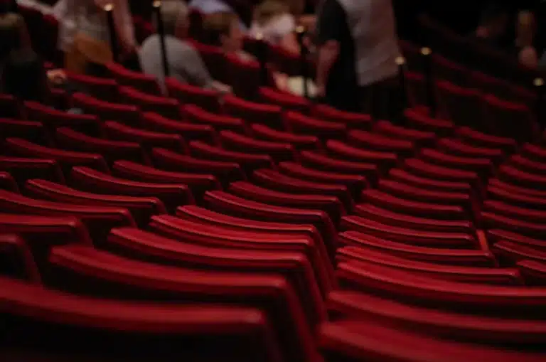 Leeg toneel met microfoon en silhouetten van publiek in een klein theater